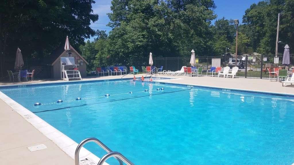 A clear blue outdoor pool with a lane rope and a small guard stand on a sunny day.